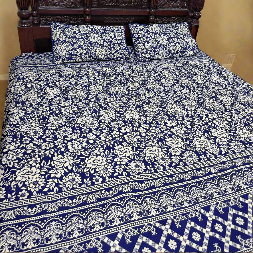 Bed with blue and white floral patterned bedding and a wooden headboard.
