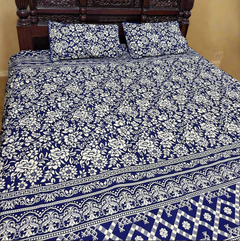 Bed with blue and white floral patterned bedding and a wooden headboard.